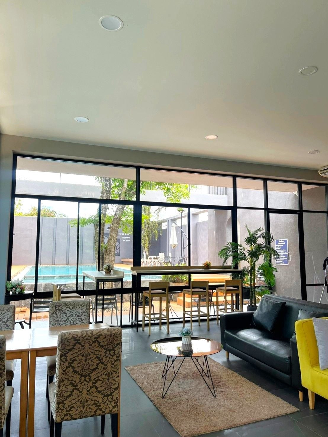 A modern interior with a pool view, a dining area, and a sofa.