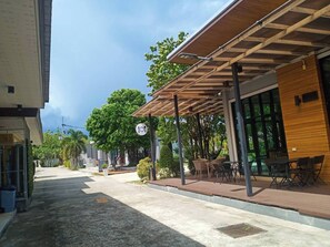 A covered outdoor seating area with tables and chairs, a clear sky, and a building with a sign that reads "101". - Seree Grand Resort (Hat Yai)