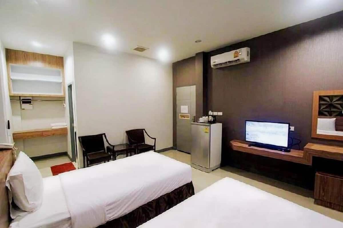 A hotel room with two beds, a desk, a television, and a minibar.