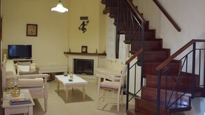 Una sala de estar con chimenea, televisor, escalera y comedor.