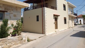 Un edificio de dos pisos con un balcón y un muro de piedra a la izquierda.