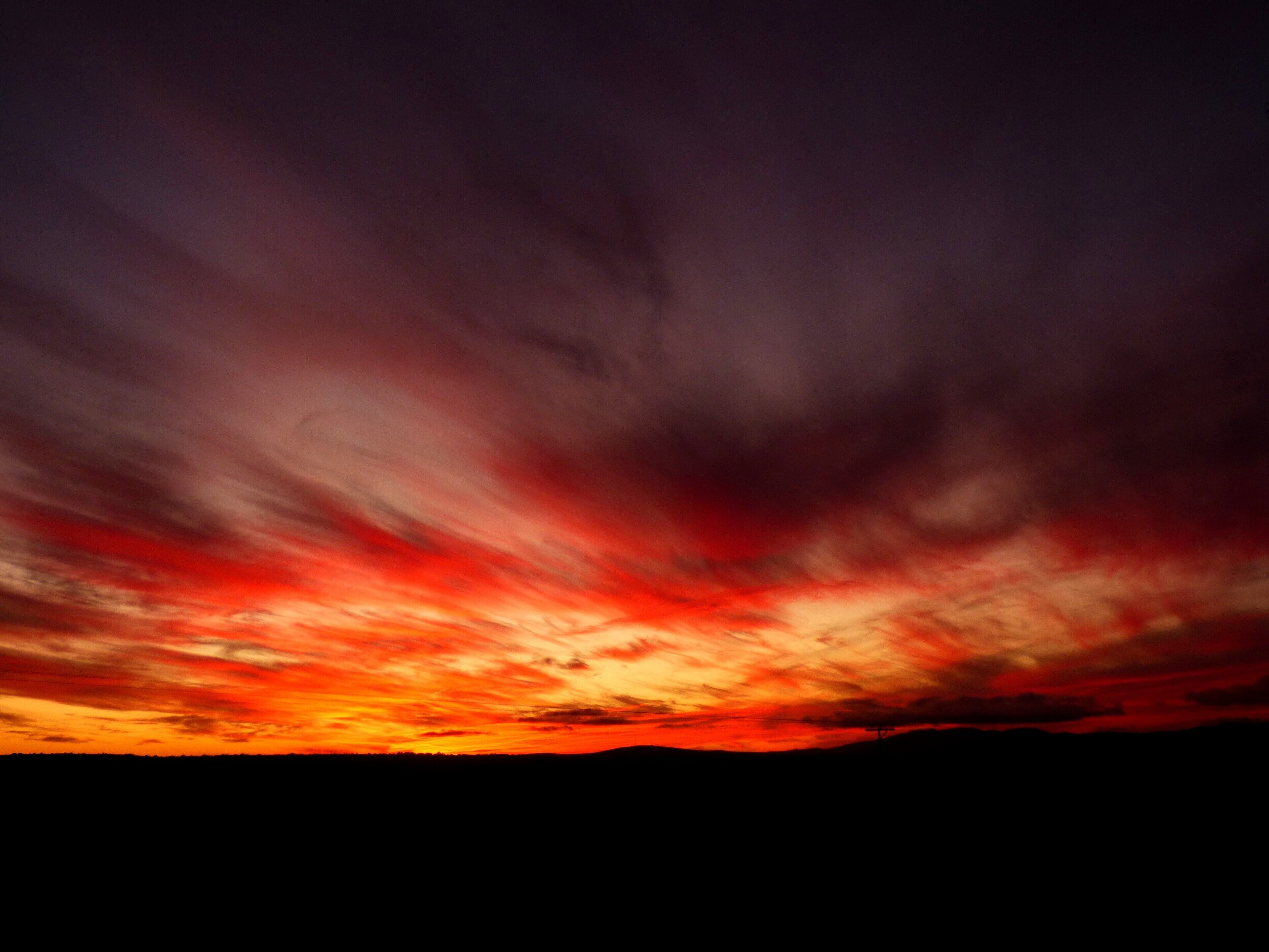 A sunset with a dark sky and red-orange clouds.
