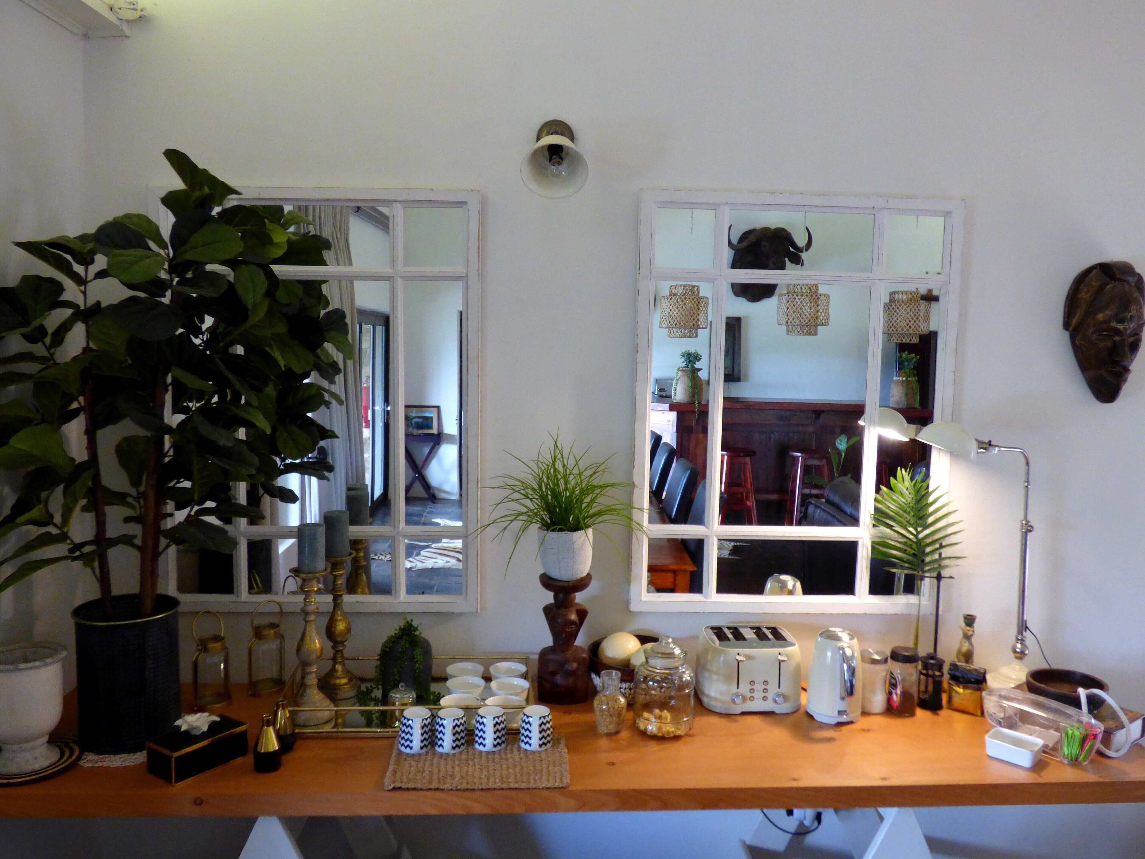 A kitchen with a wooden countertop, various kitchen appliances, and potted plants.