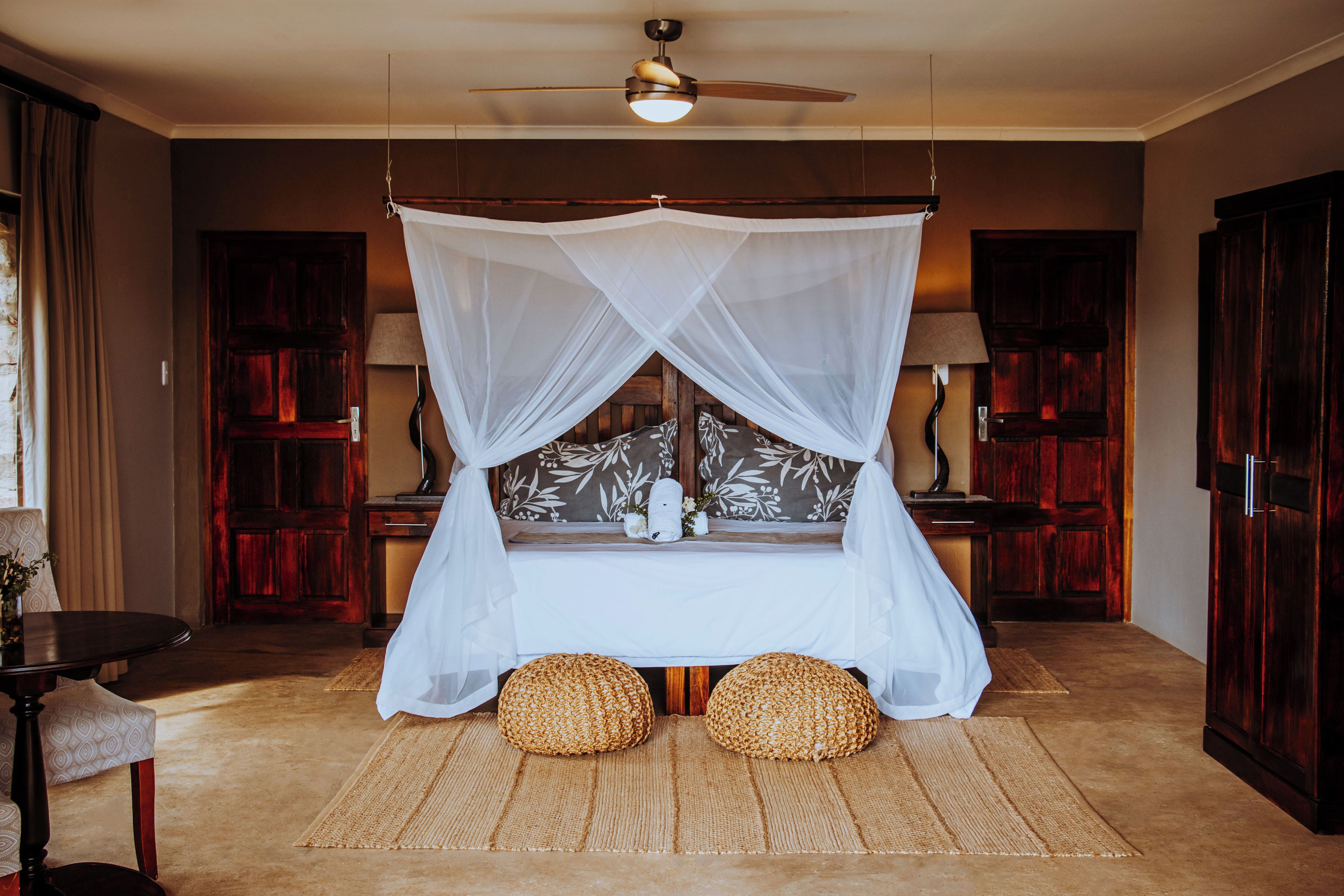 Une chambre à coucher avec un lit à baldaquin, deux lampes de chevet, un banc en bois et une grande armoire.