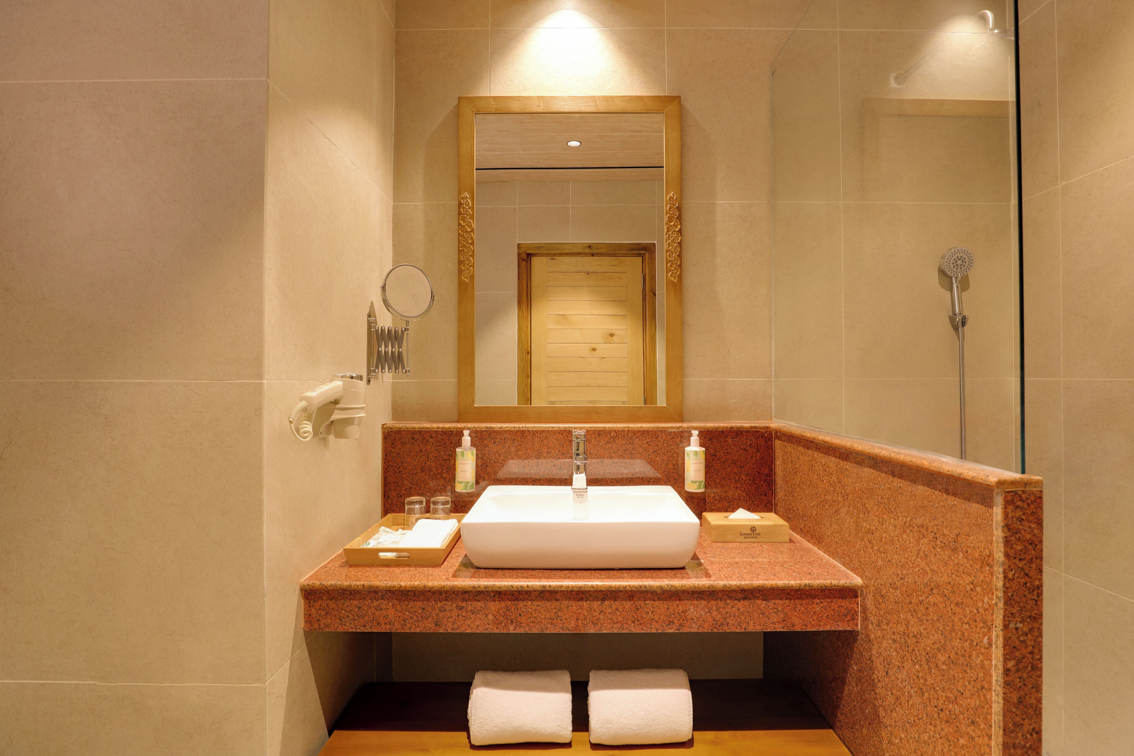 A bathroom with a large mirror, a sink, and a shower.