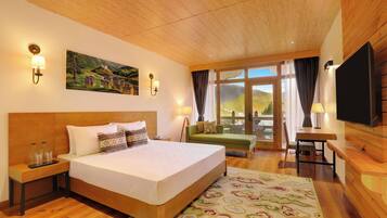 A hotel room with a large bed, wooden headboard, bedside lamps, a flat-screen TV, a painting on the wall, and a view through the window.