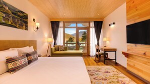 A hotel room with a large bed, a desk, a chair, and a TV.