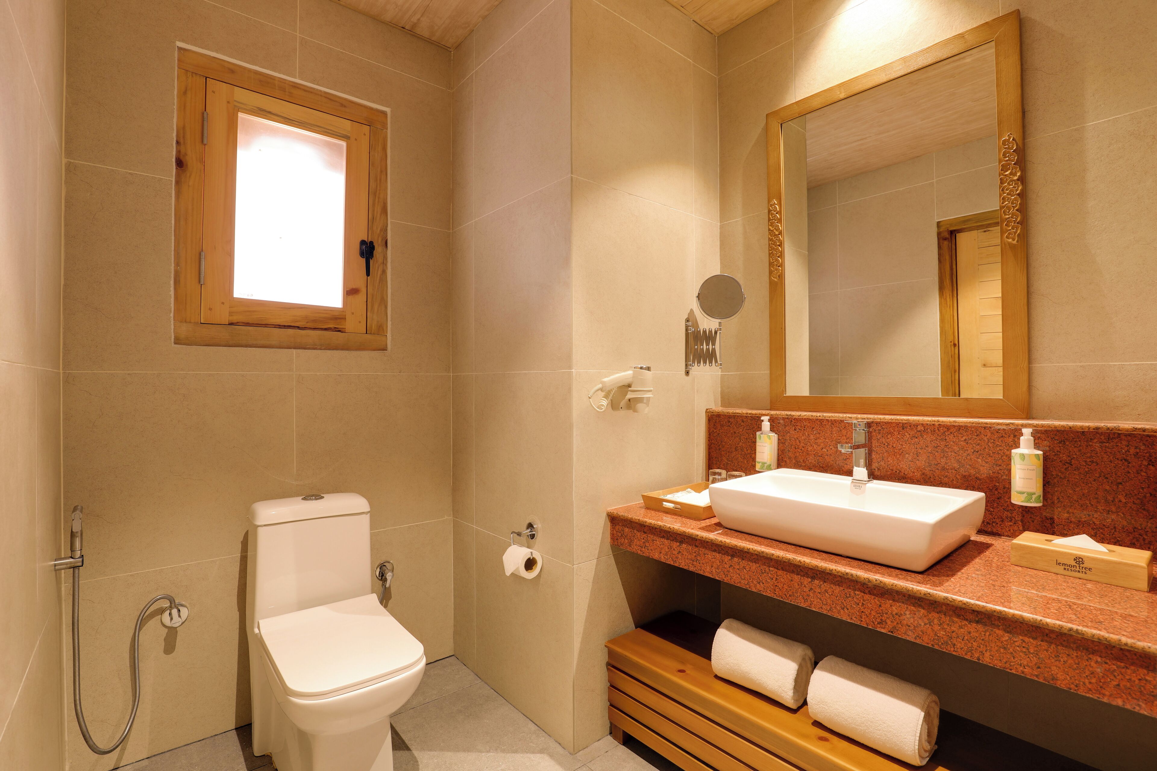 A bathroom with a toilet, sink, mirror, towel rack, and a window.