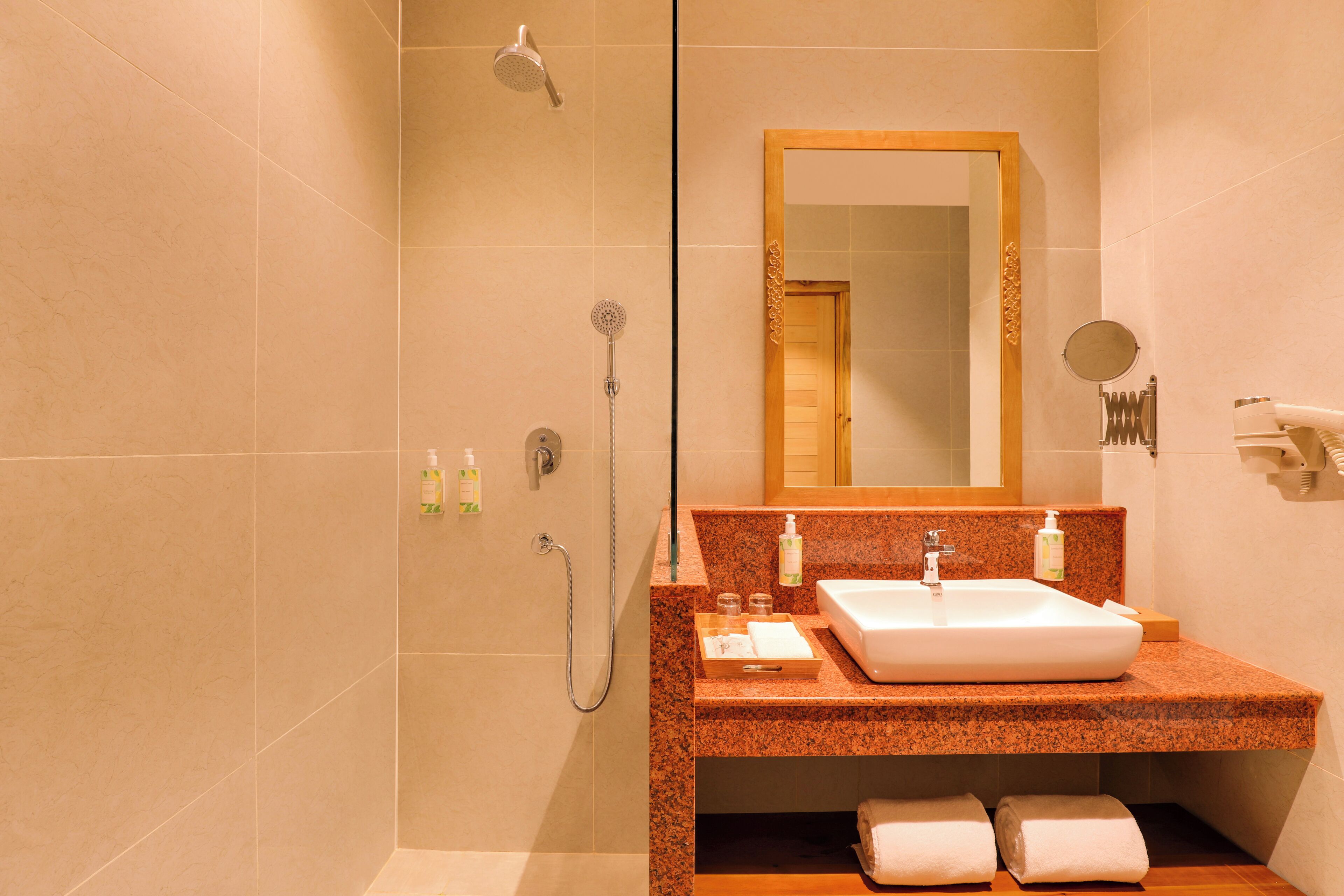 A bathroom with a sink, mirror, shower, and towel rack.