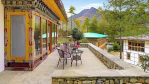A traditional building with a balcony, stone walls, and a view of mountains.