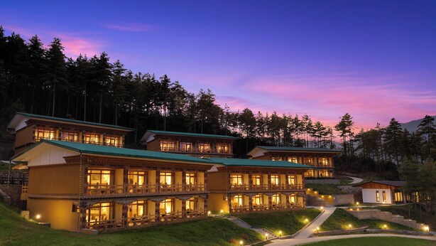 A multi-story hotel with a green roof, multiple balconies, and a well-lit exterior.