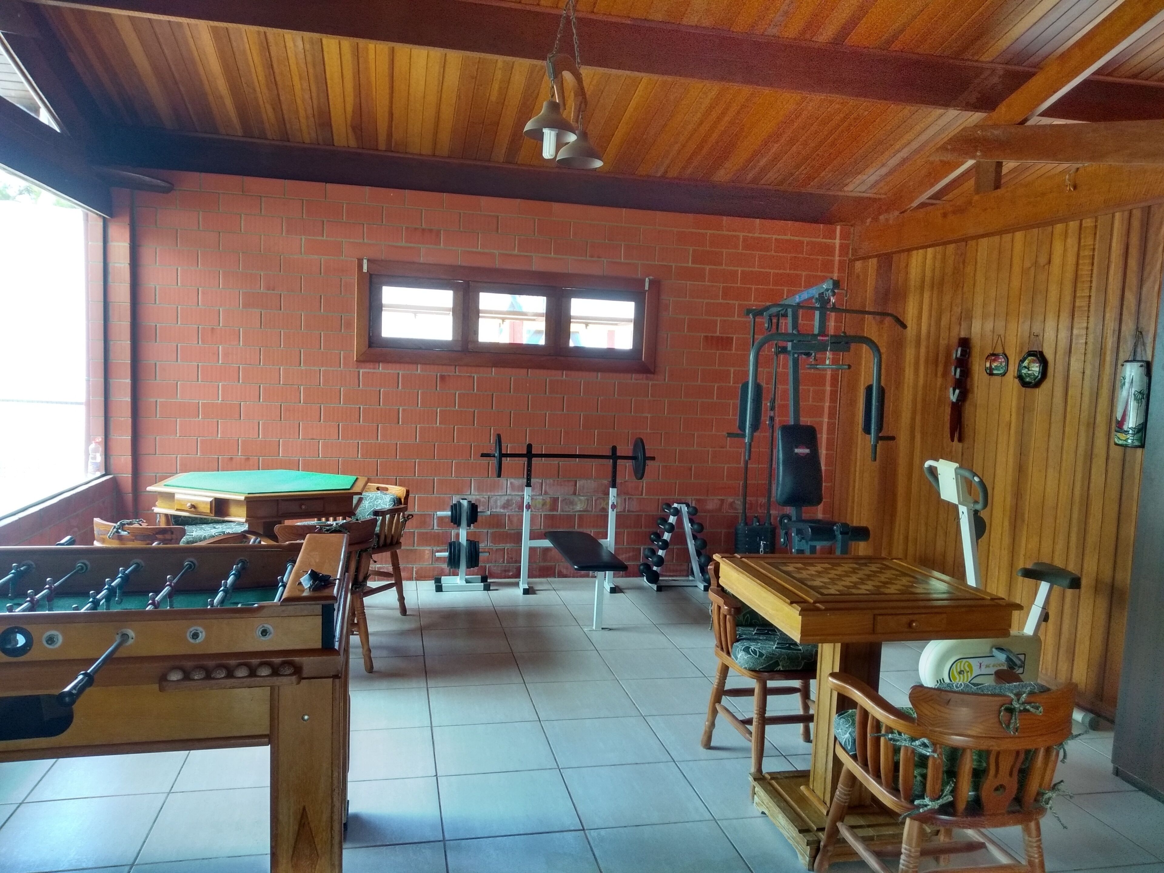 A room with a foosball table, a weightlifting area, and a billiards table.
