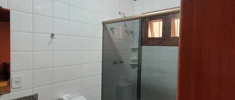 A bathroom with a toilet, sink, and glass shower enclosure.