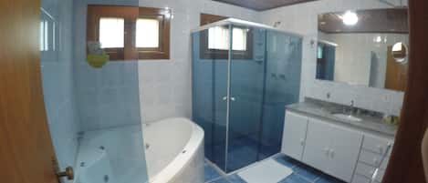 Un baño con bañera, cabina de ducha de vidrio y lavamanos.