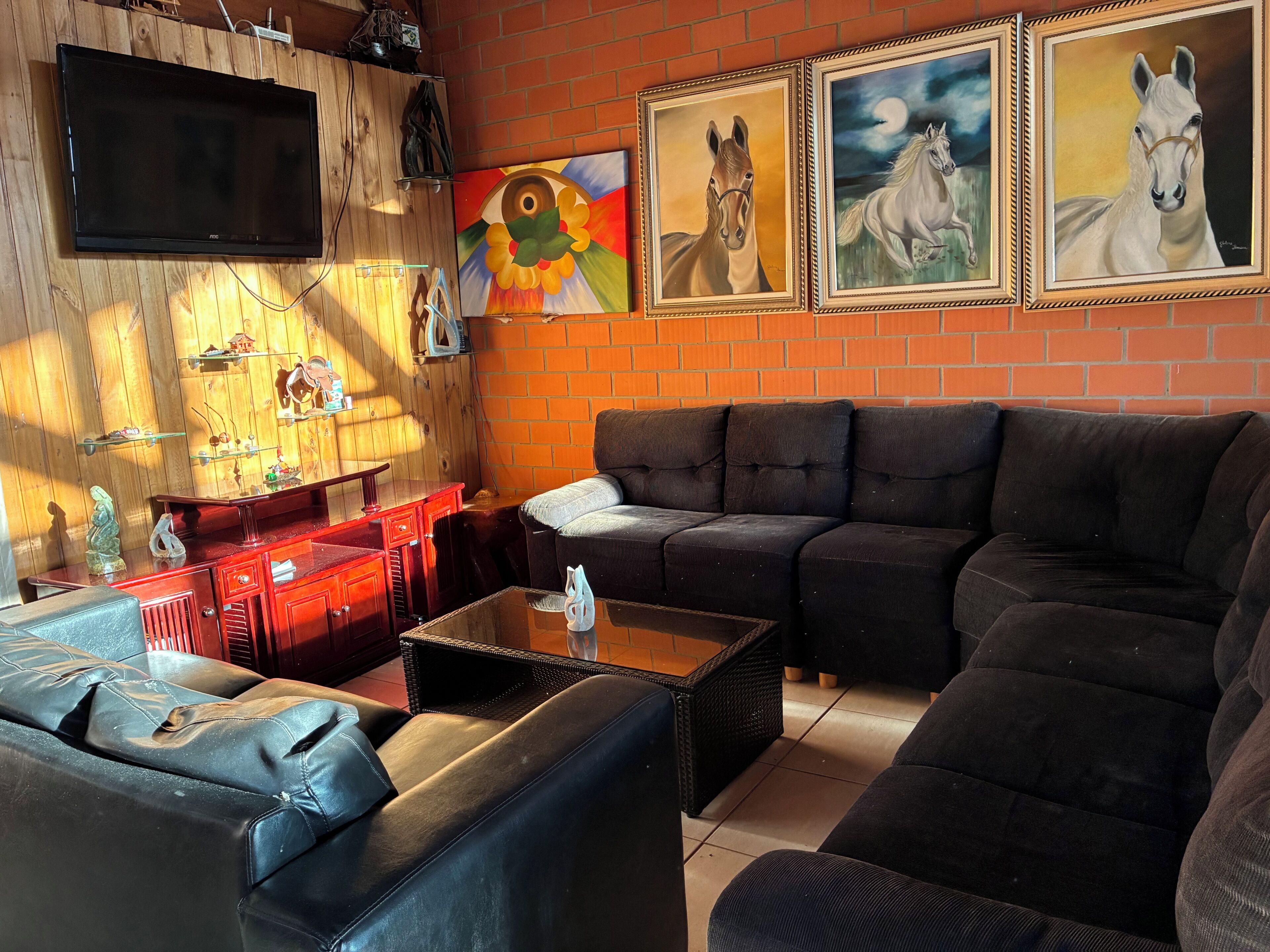 Un salon avec un canapé, une table basse, un téléviseur et des œuvres d’art accrochées au mur.