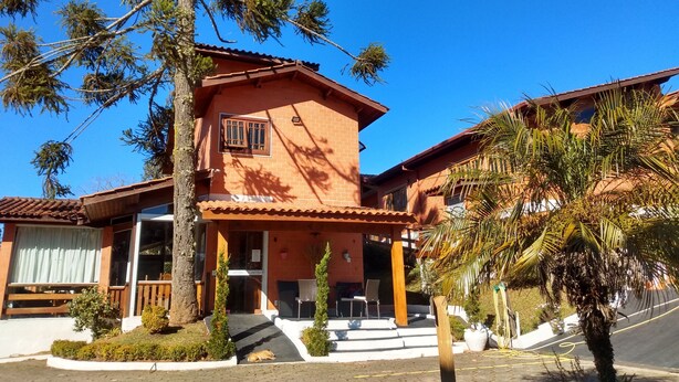 Un edificio de dos pisos con fachada de ladrillo, un balcón y una pequeña zona de porche.