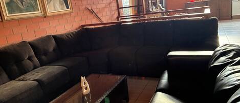 Una sala de estar moderna con un sofá modular, una mesa de centro de vidrio y dos cuadros enmarcados con caballos en la pared.