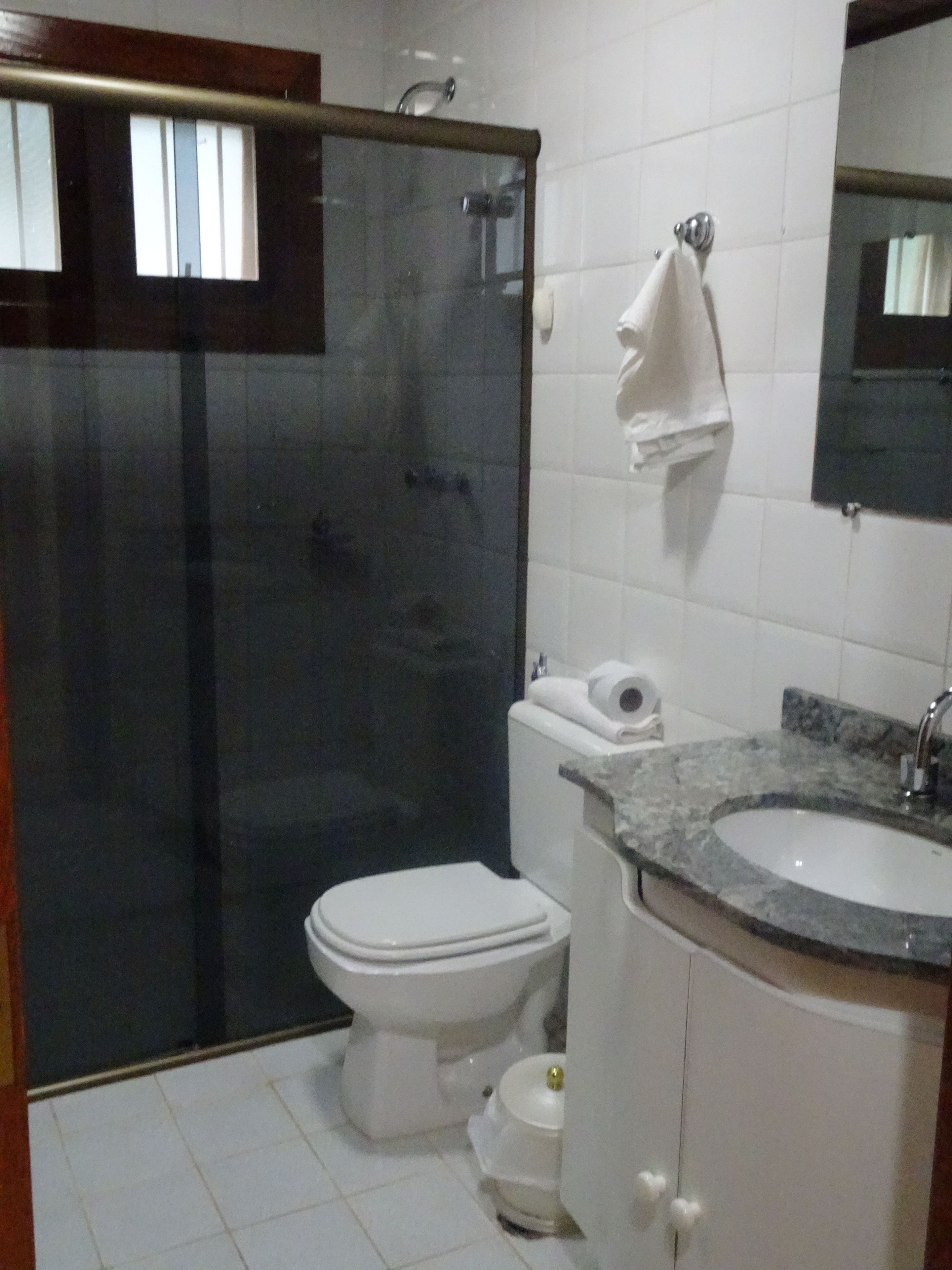 Un baño con cabina de ducha de vidrio, inodoro, lavamanos y espejo.