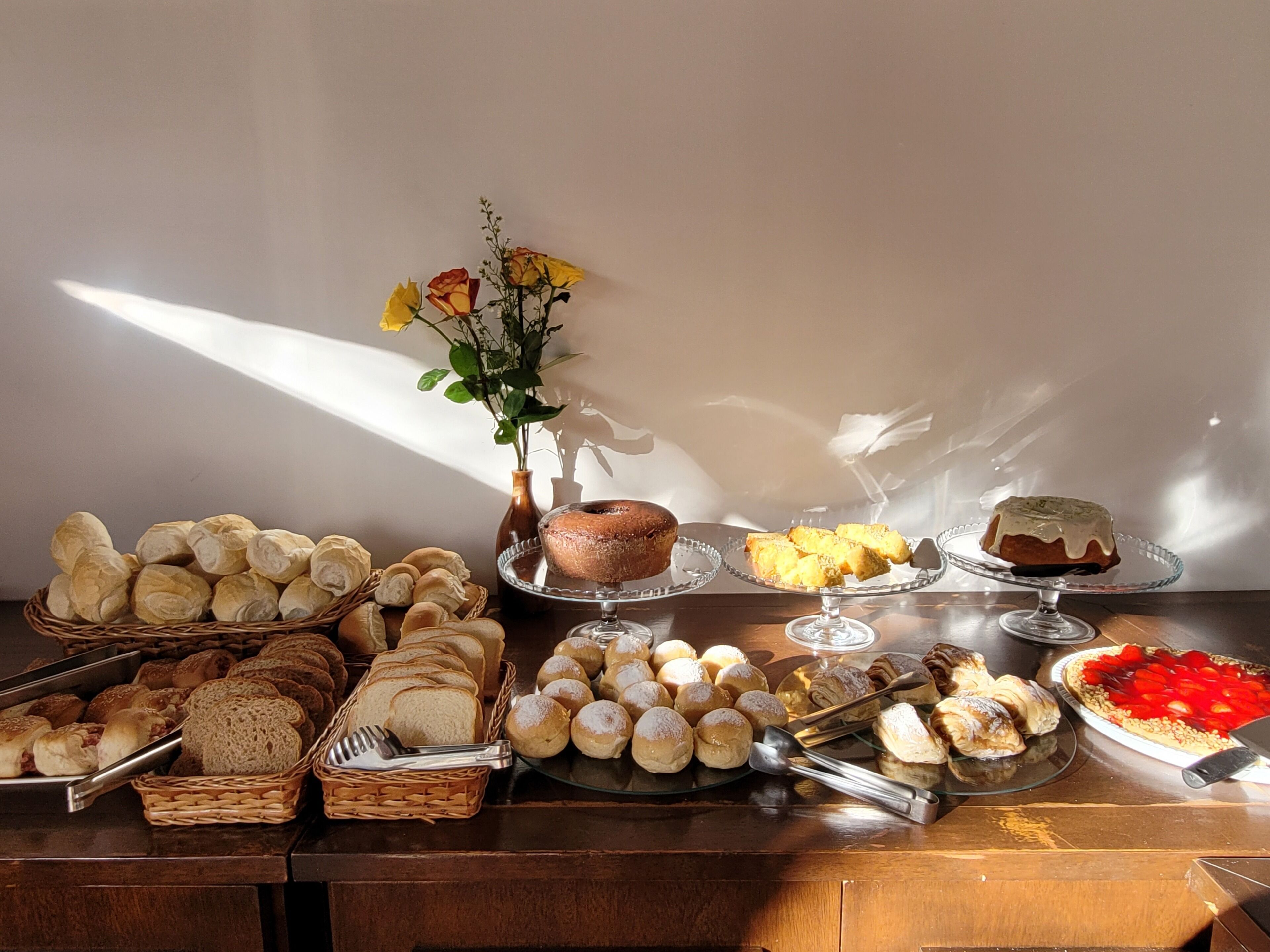 A buffet table with various breads, pastries, and a cake.