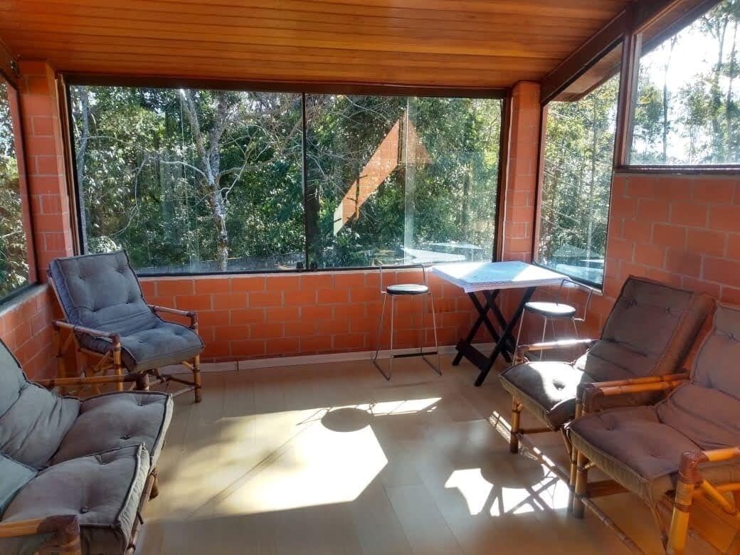 A covered patio with brick walls, large windows, and two tables with chairs.