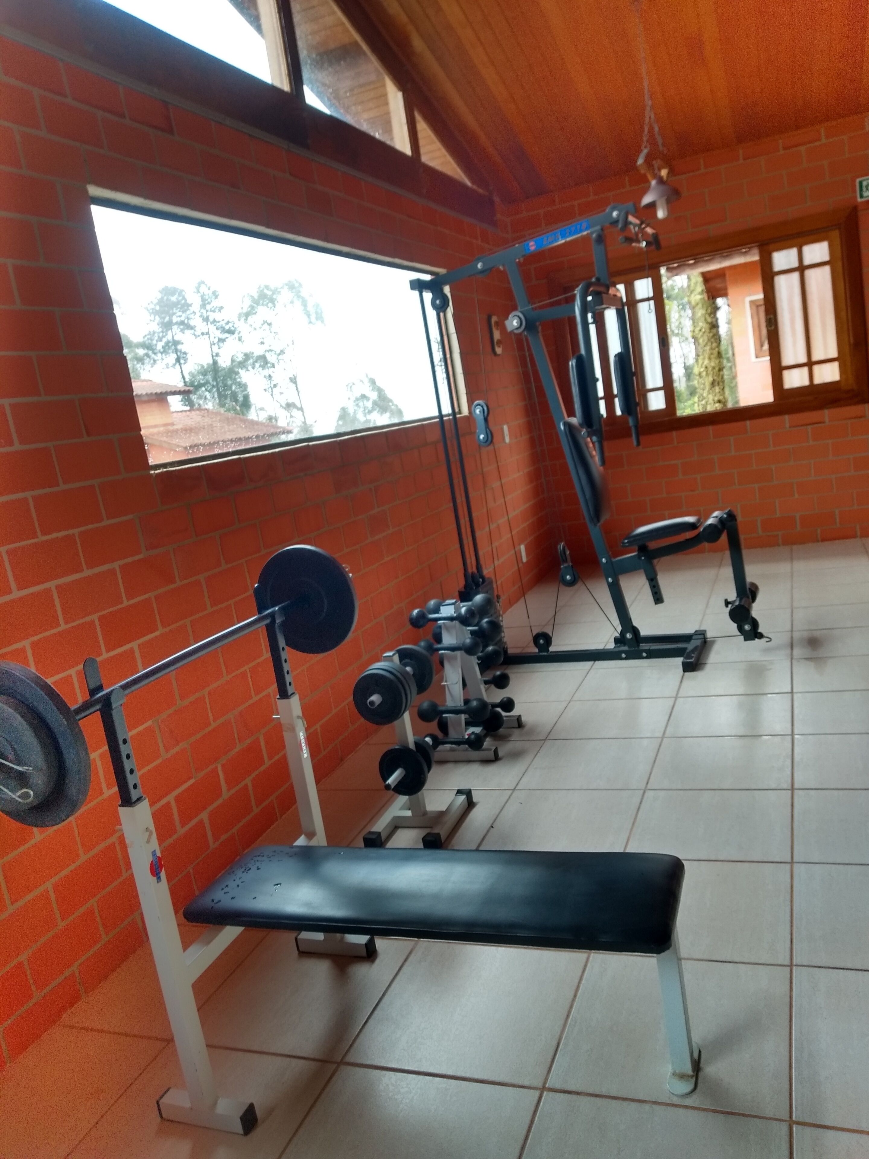 Ein Fitnessraum mit Gewichten, einer Hantelbank und einer Ziegelwand.