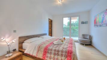 Quarto com cama, mesa de cabeceira e uma cadeira.