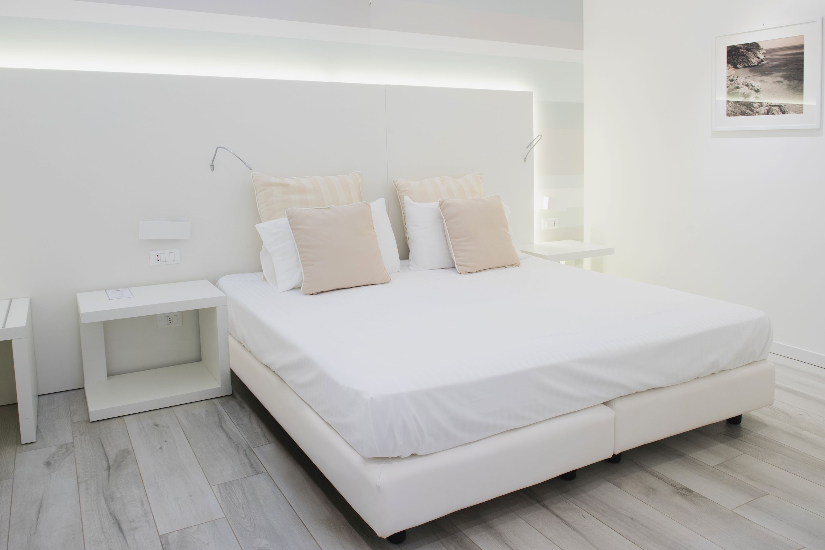 Quarto moderno com uma cama grande, mesas de cabeceira e um criado-mudo.