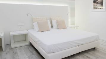Quarto moderno com uma cama grande, mesas de cabeceira e um criado-mudo.