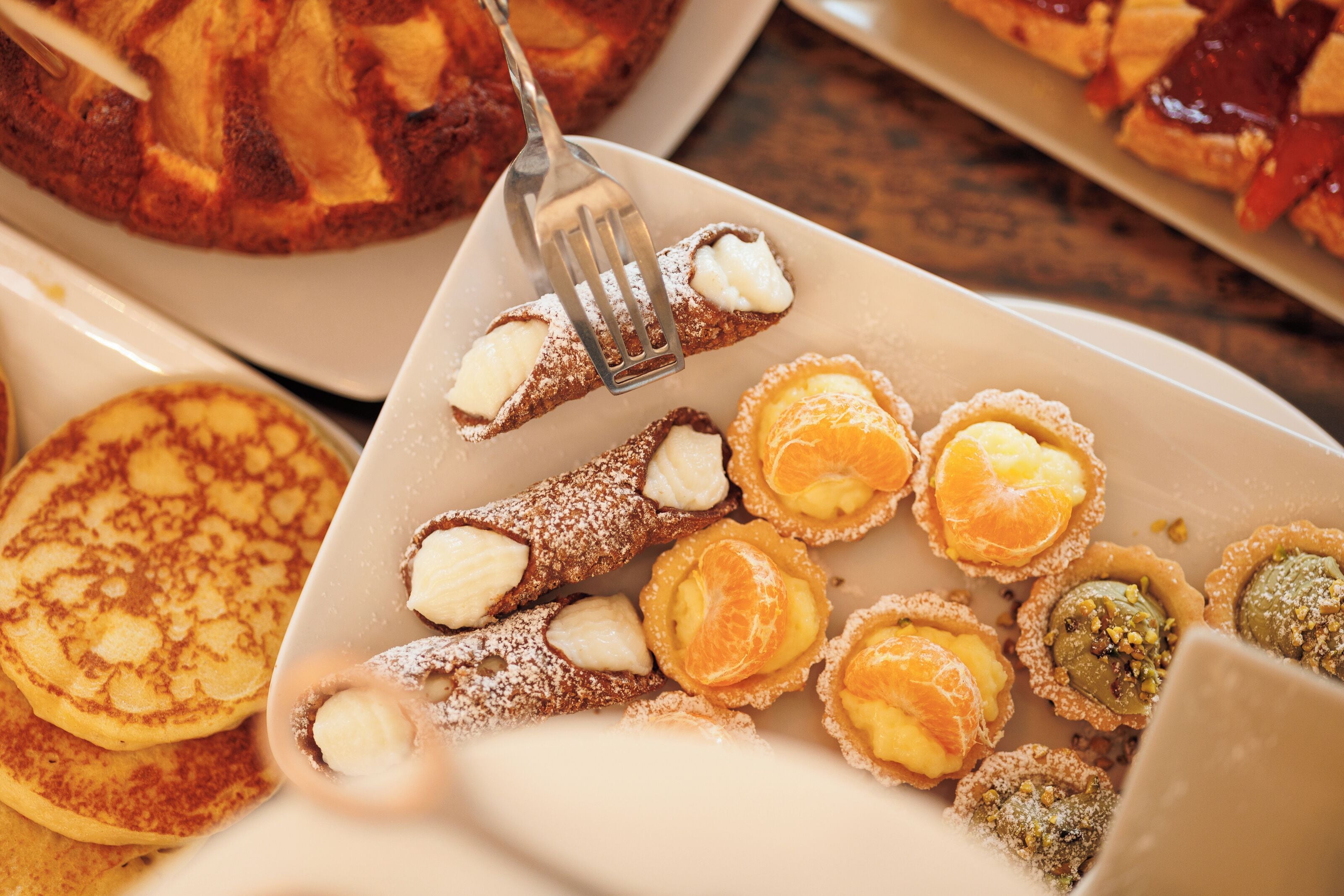 A variety of pastries including cannoli and cannoli shells on a plate.