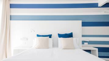 A hotel room with a large bed, two bedside tables, and a headboard with a blue and white striped pattern.
