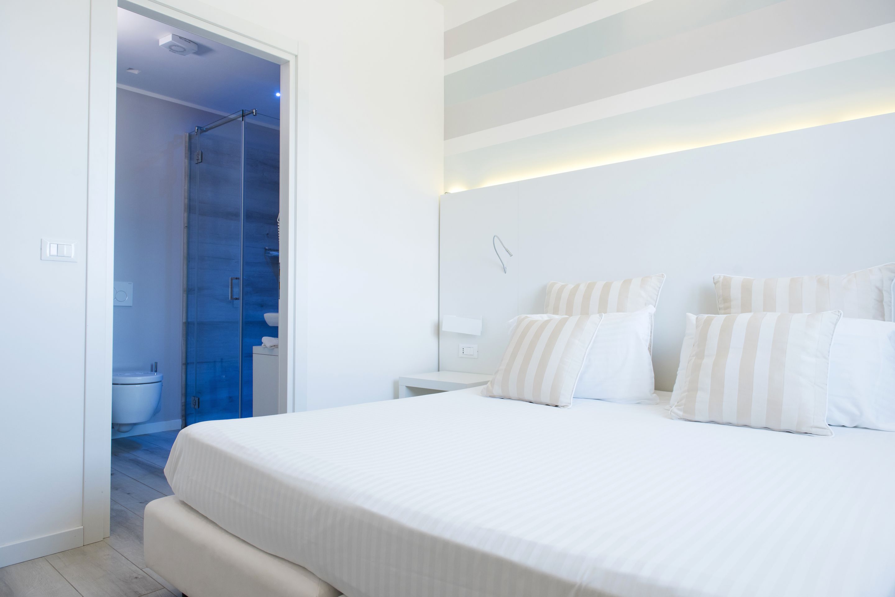 A modern bedroom with a large bed, a bedside table, and a glass shower enclosure.