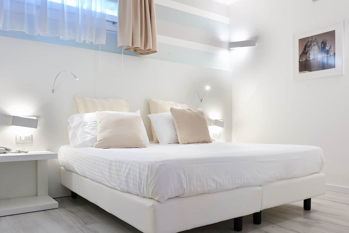 A modern bedroom with a large bed, bedside tables, and a wall-mounted lamp.