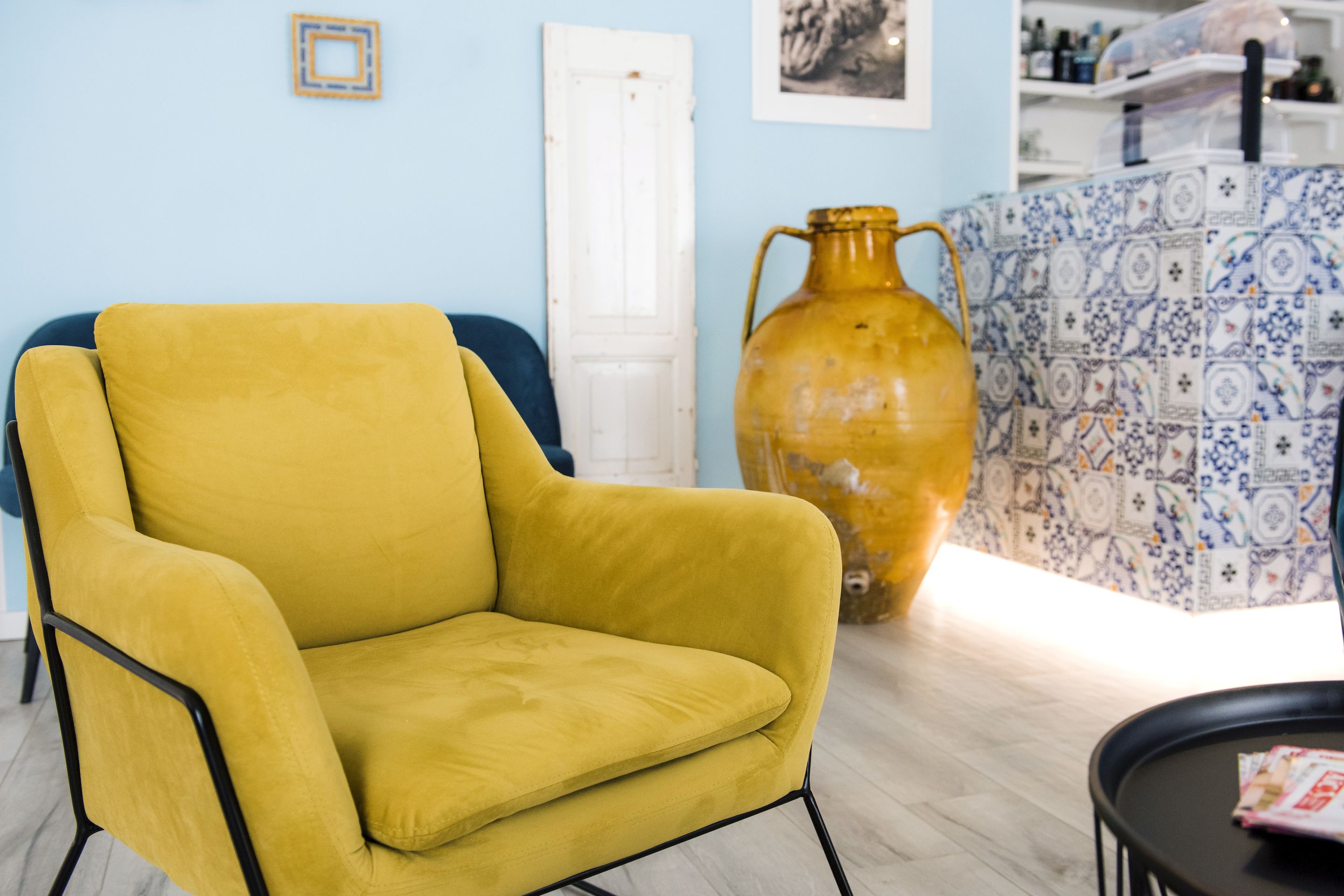 A yellow armchair in a room with a tiled backsplash and a white door.