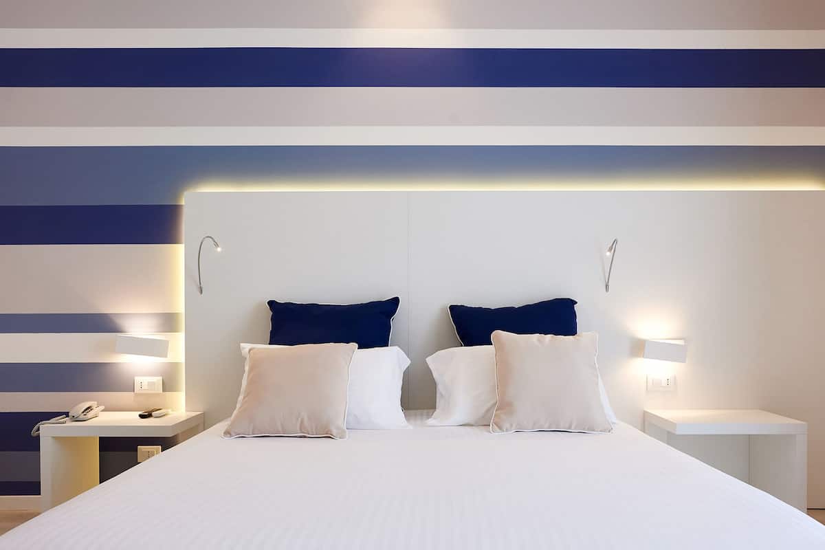 A hotel room with a large bed, two bedside tables, a desk, and a phone.
