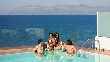 Zona junto a la piscina con vista despejada al océano y montañas a lo lejos.