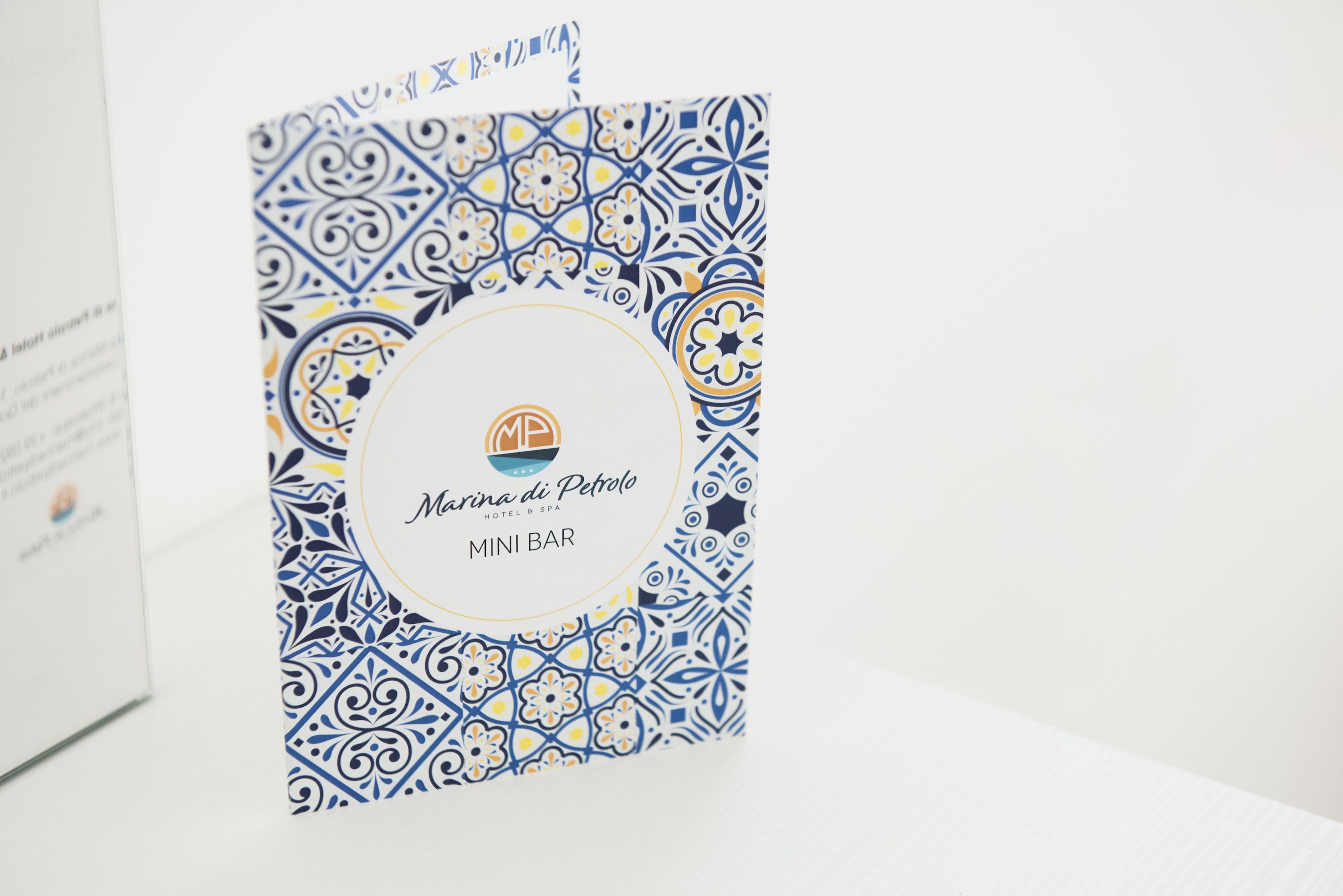 Une brochure pour le Marina di Petrolio Hotel & Spa, présentant le MINI BAR, orné d’un motif décoratif bleu et jaune.