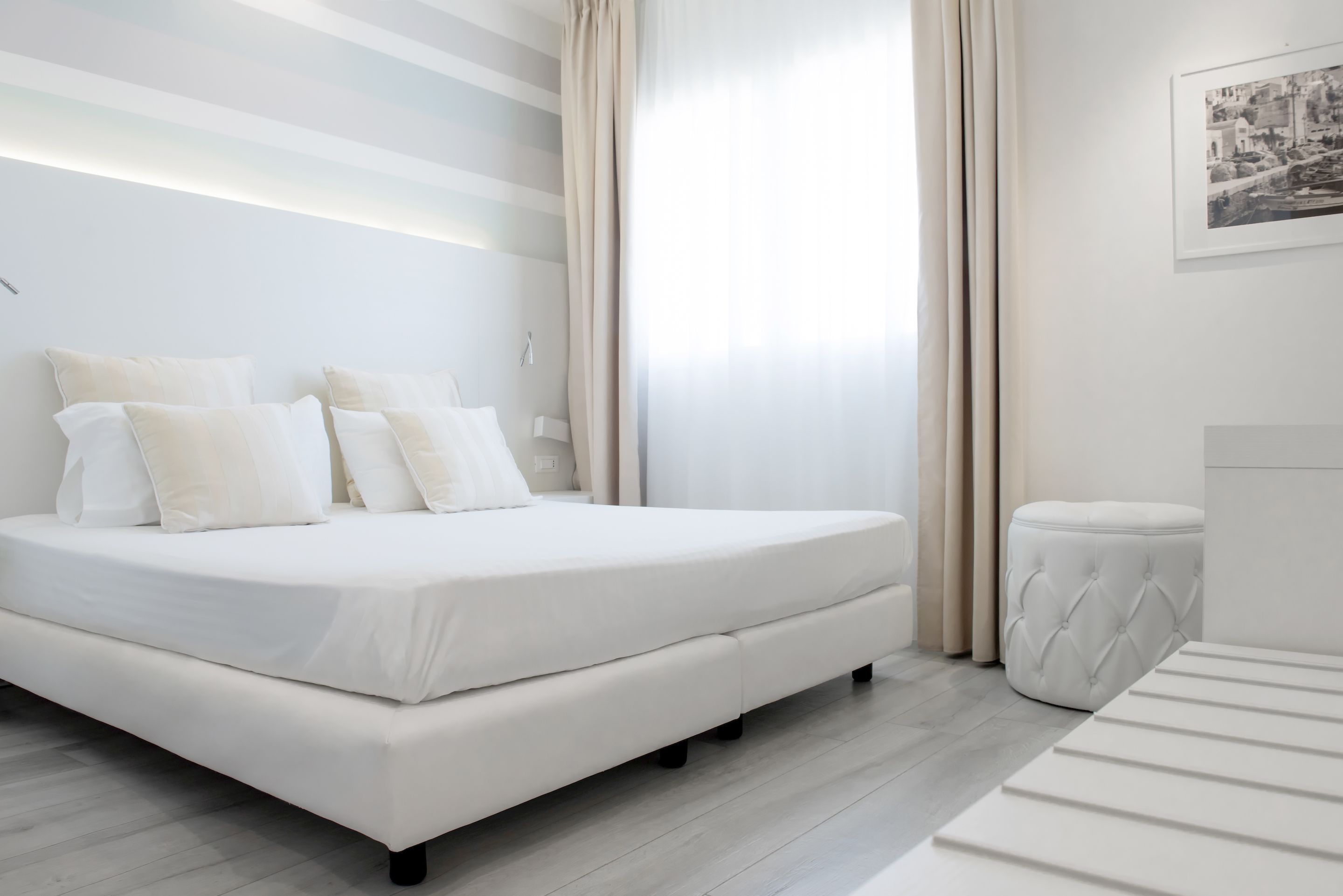 A modern bedroom with a large bed, a bedside table, and a window with curtains.