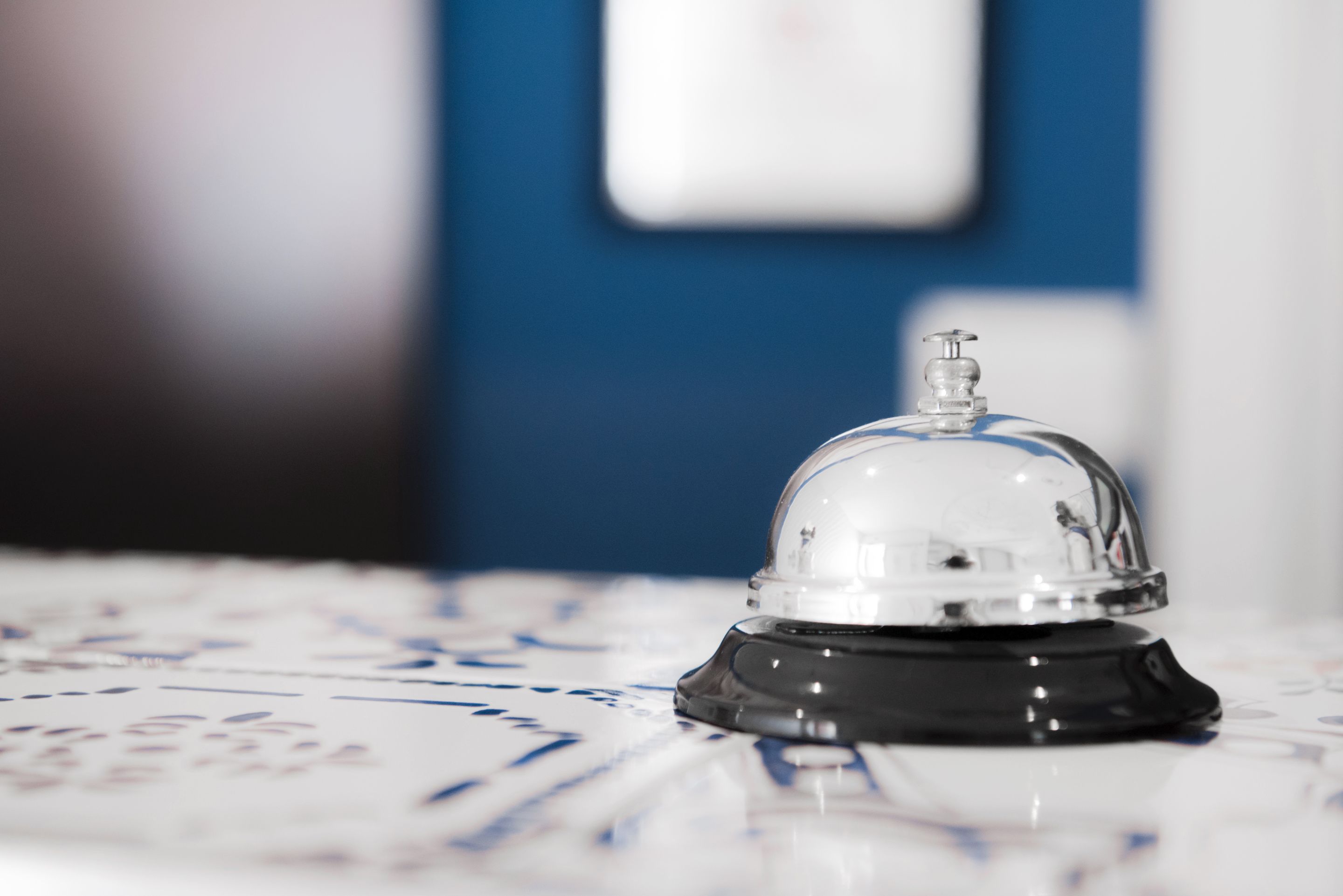 A clear glass bell on a reflective surface with a blurred background.