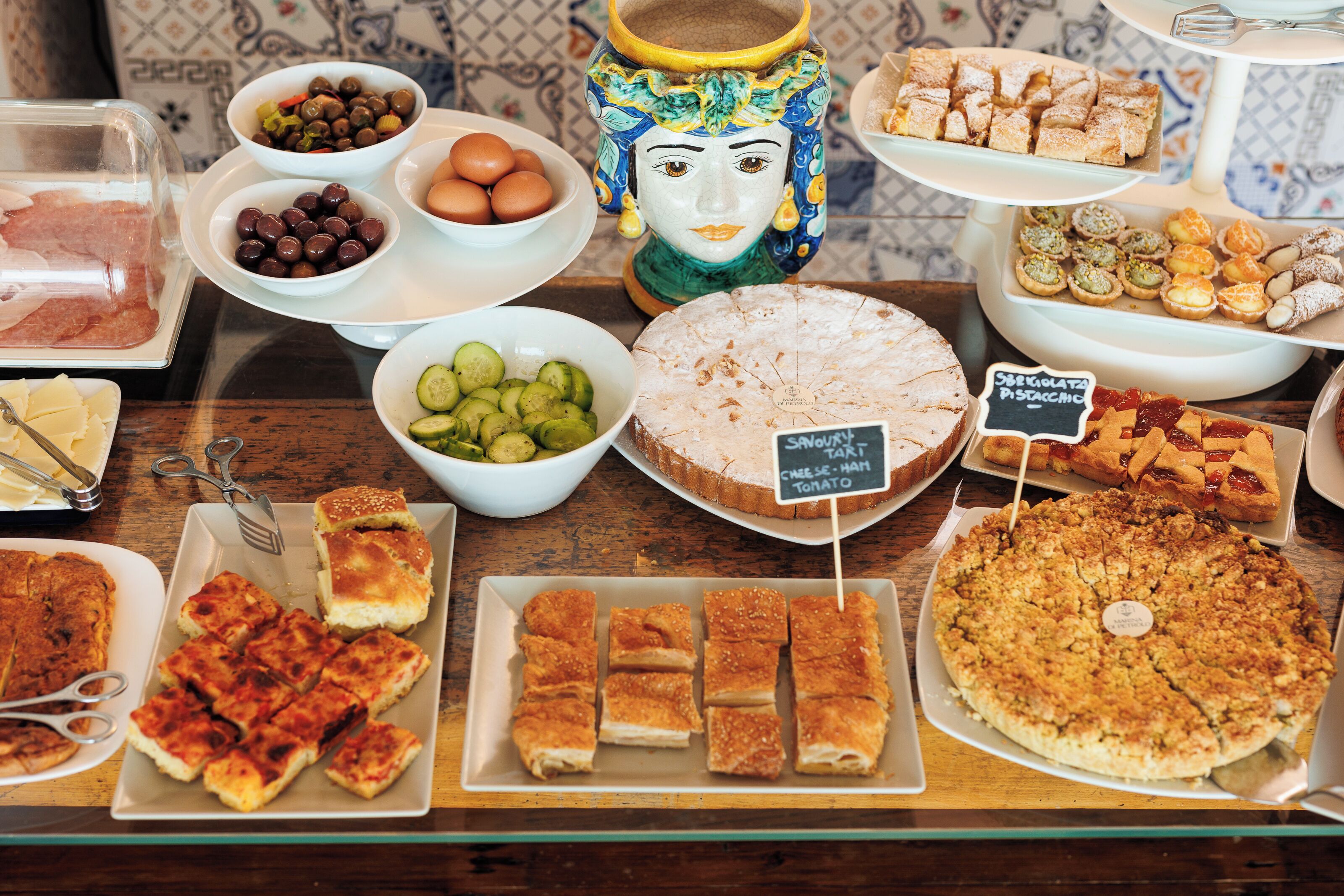 Une variété d’aliments sont présentés sur une table, notamment des tartes, des pâtisseries et d’autres produits de boulangerie.
