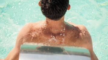 Uma pessoa em uma piscina com água espirrando ao redor.