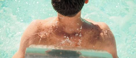 A person in a swimming pool with water splashing around them.