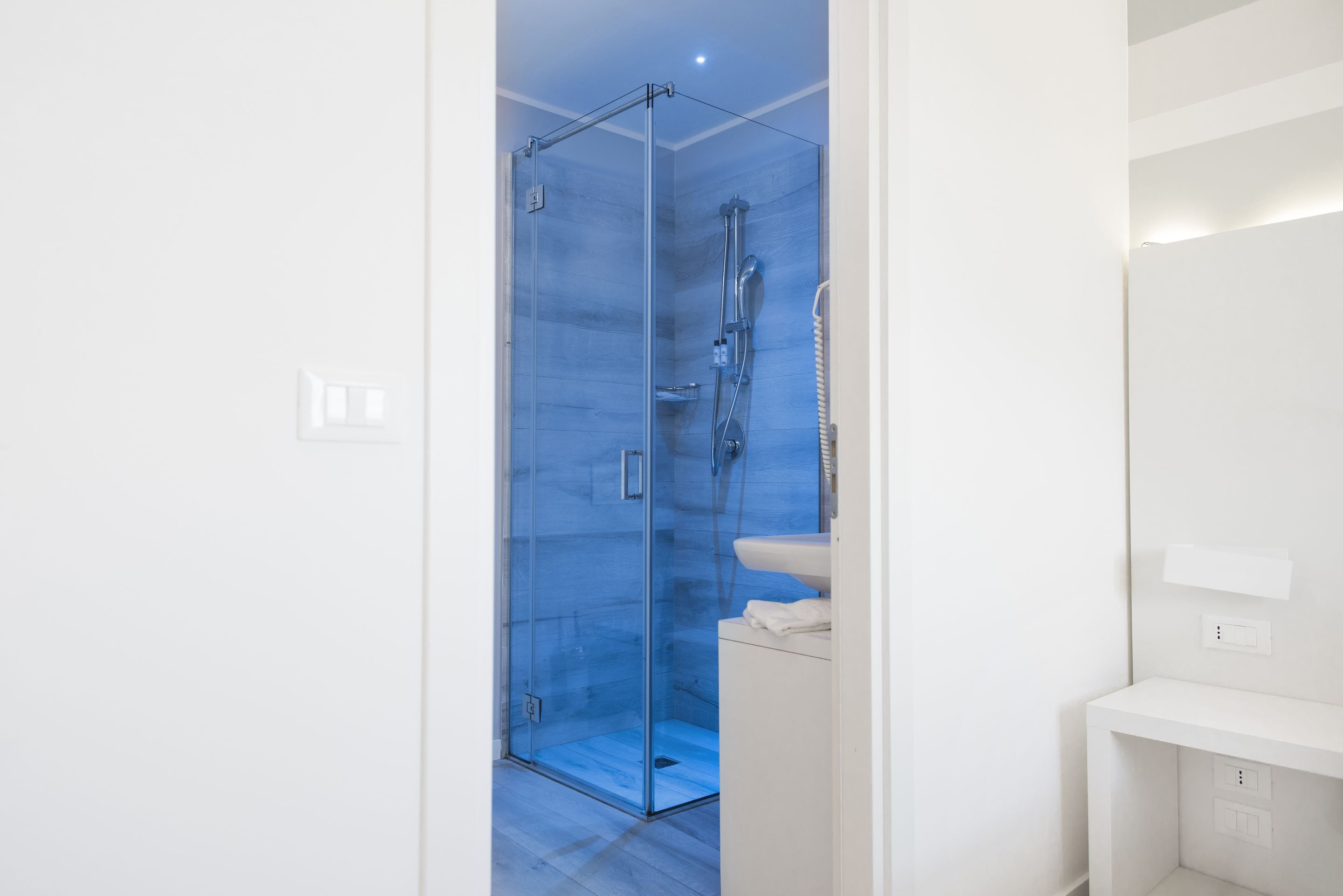 A modern bathroom with a glass-enclosed shower, a white sink, and a mirror.