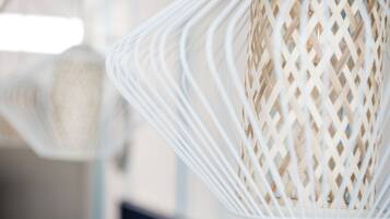 A close-up of a woven, conical light fixture with a lattice design.