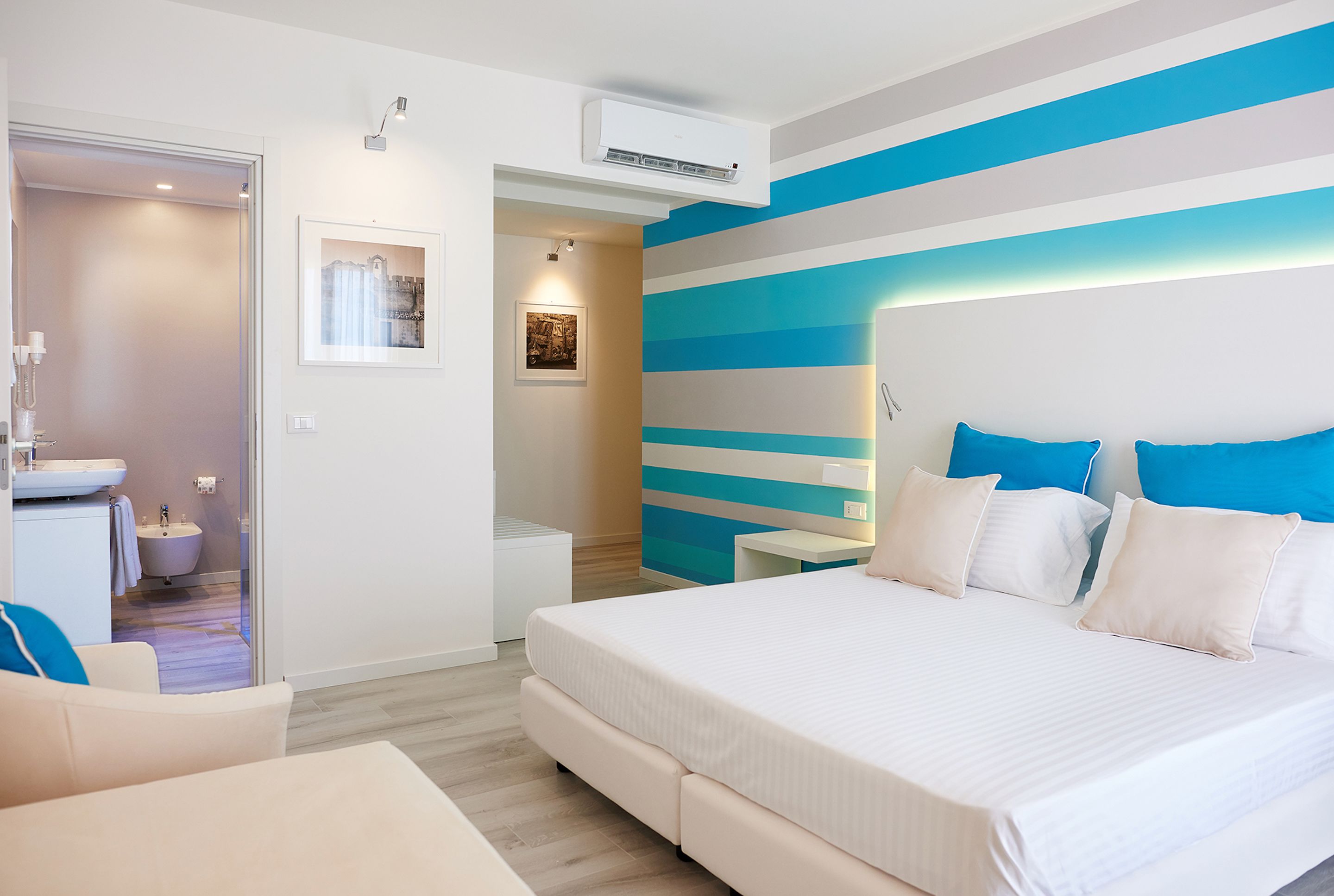 A modern bedroom with a large bed, a bedside table, a nightstand, and a bathroom visible through an open door.