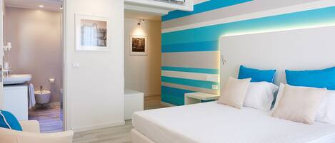 A modern bedroom with a large bed, a bedside table, a nightstand, and a bathroom visible through an open door.