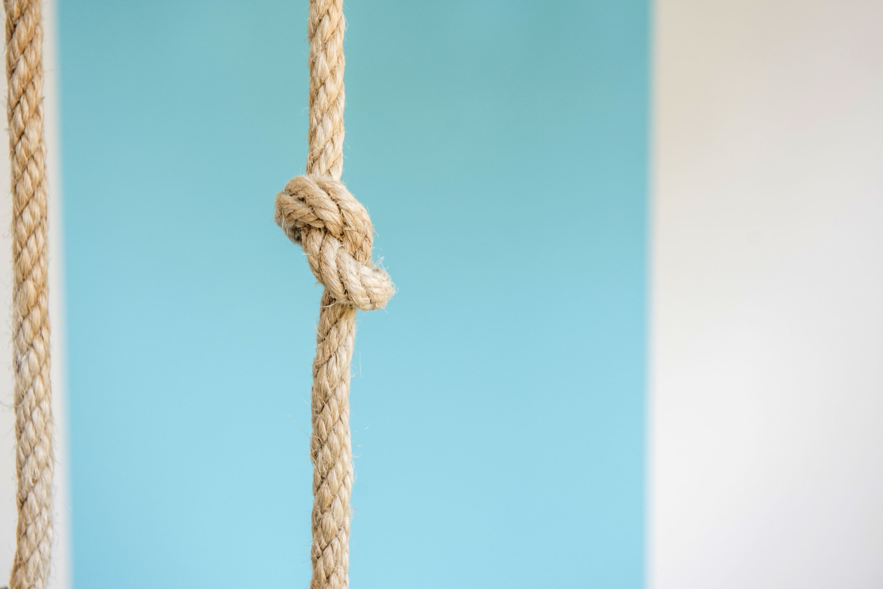 A close-up of a rope tied in a knot against a blue background.