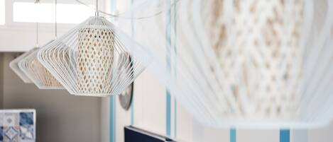 A modern office space with a hanging white woven light fixture, a black desk, and a blue-striped wall.