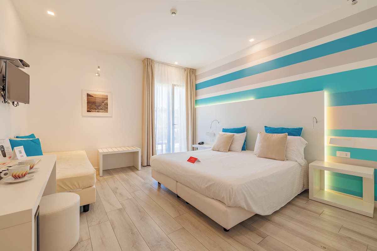 A modern hotel room with a large bed, a desk, and a chair.
