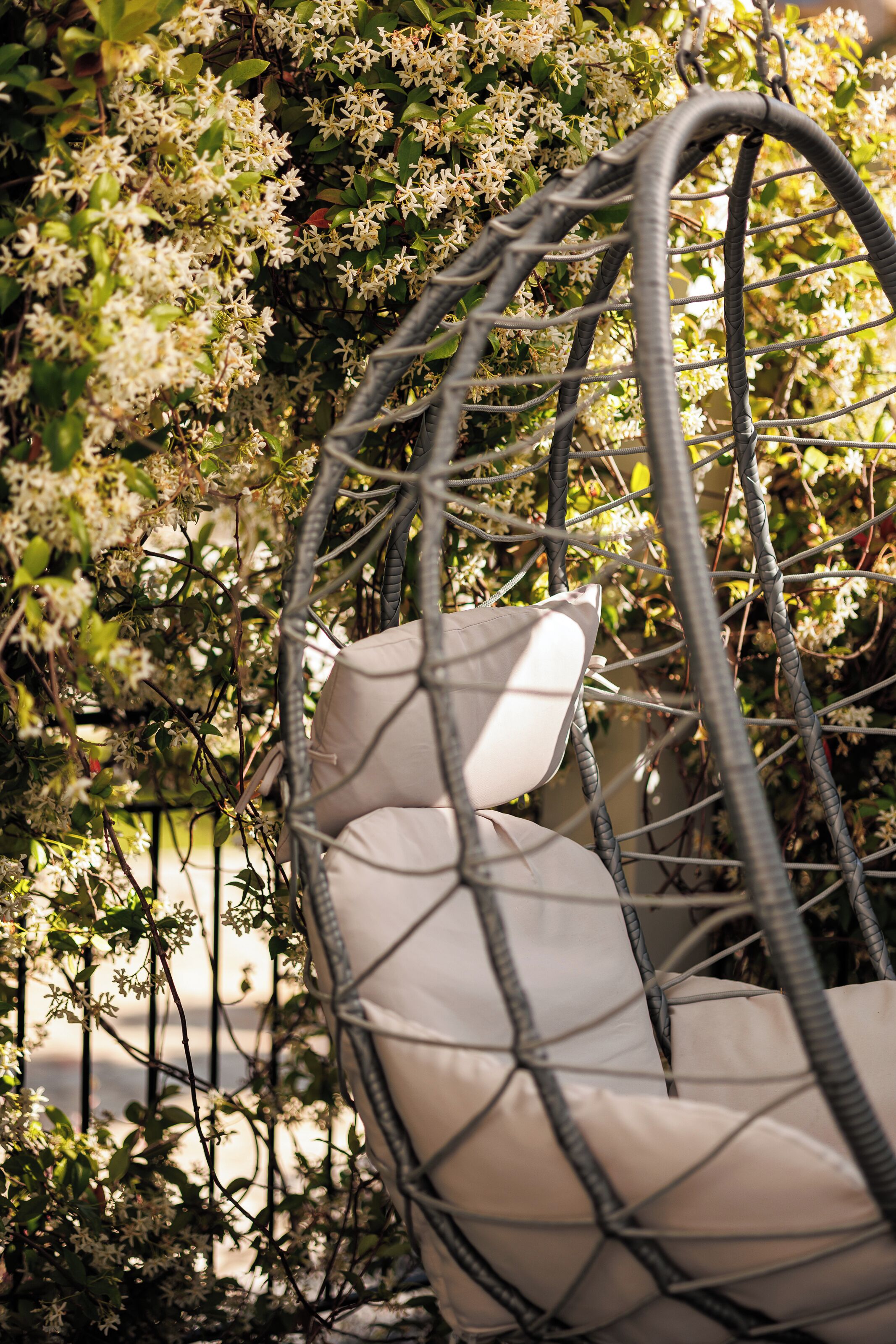 A wicker chair with a cushion in a garden setting.