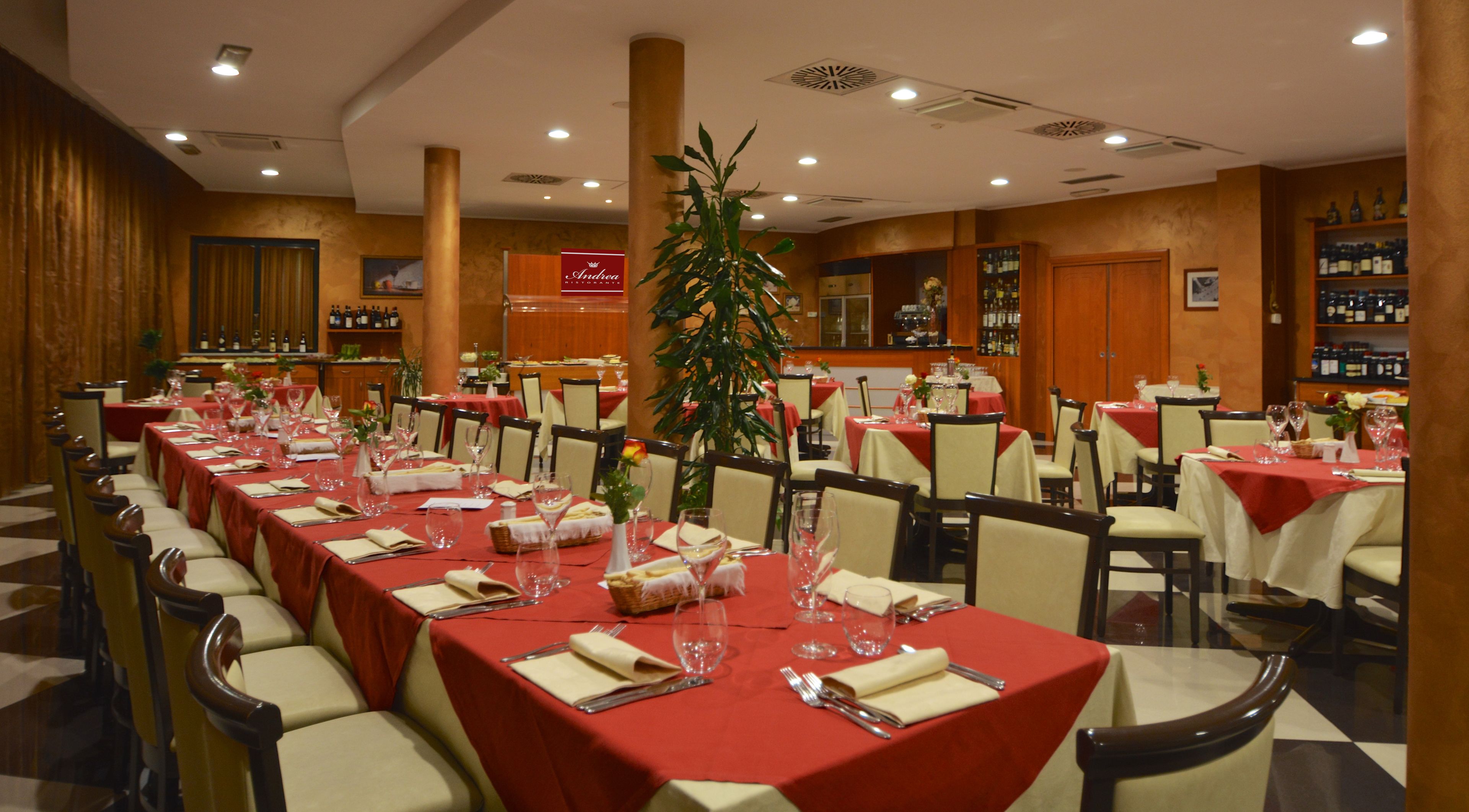 Un restaurante con mesas largas, manteles rojos y sillas.